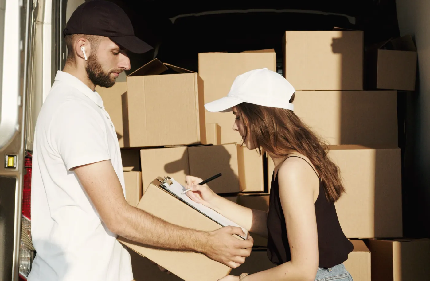 Courier team member confirming a delivery with a signature at the back of a loaded van