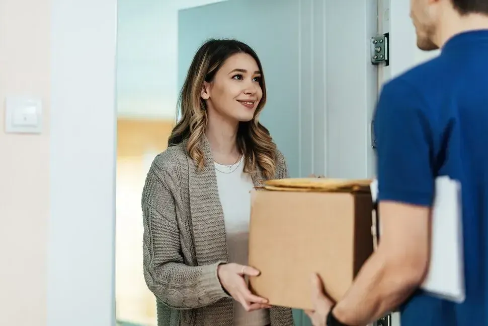 Courier handing a package to a smiling customer at her door